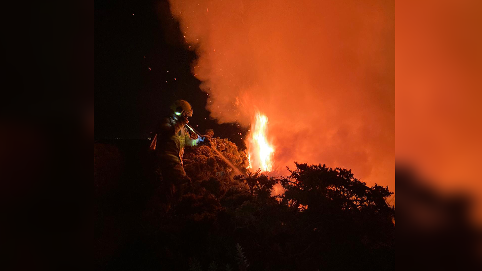 A firefighter is tackling a fire on a cliff side