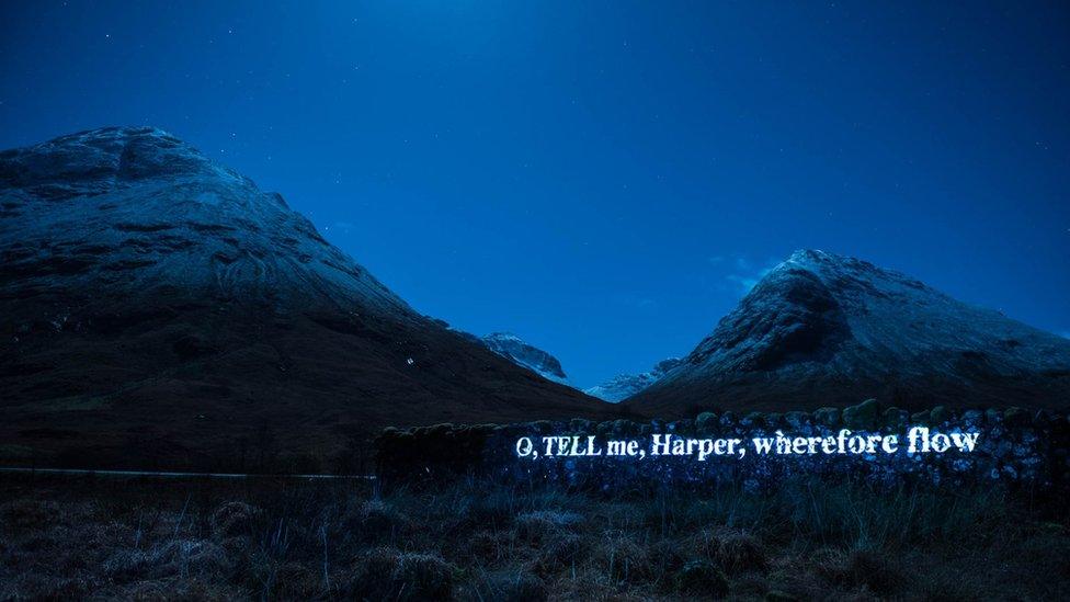 Words of poem beamed on to a dyke in Glencoe