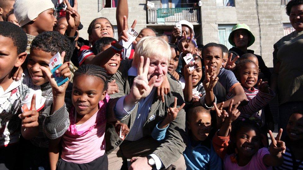 Boris Johnson pictured with a group of children giving a peace sign in Cape Town