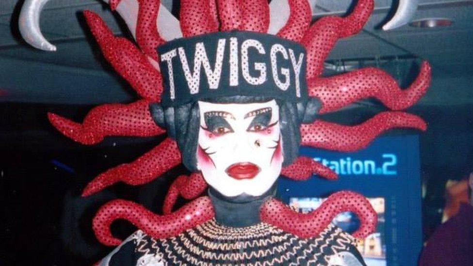 Twiggy wearing a headpiece with red snake-like features, which says Twiggy in the middle