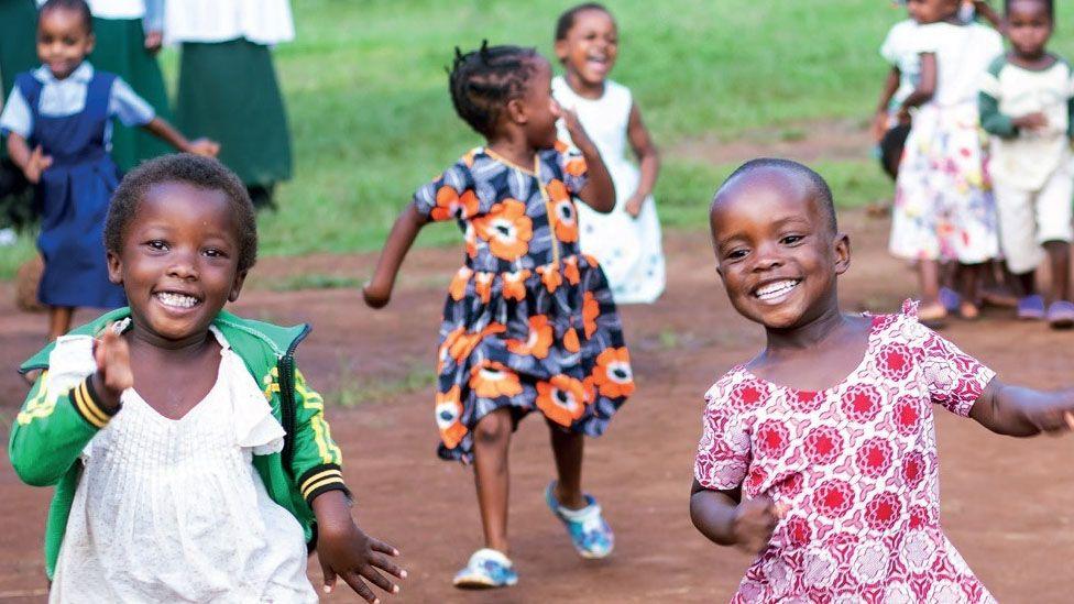 Young African children running and smiling in bright clothes