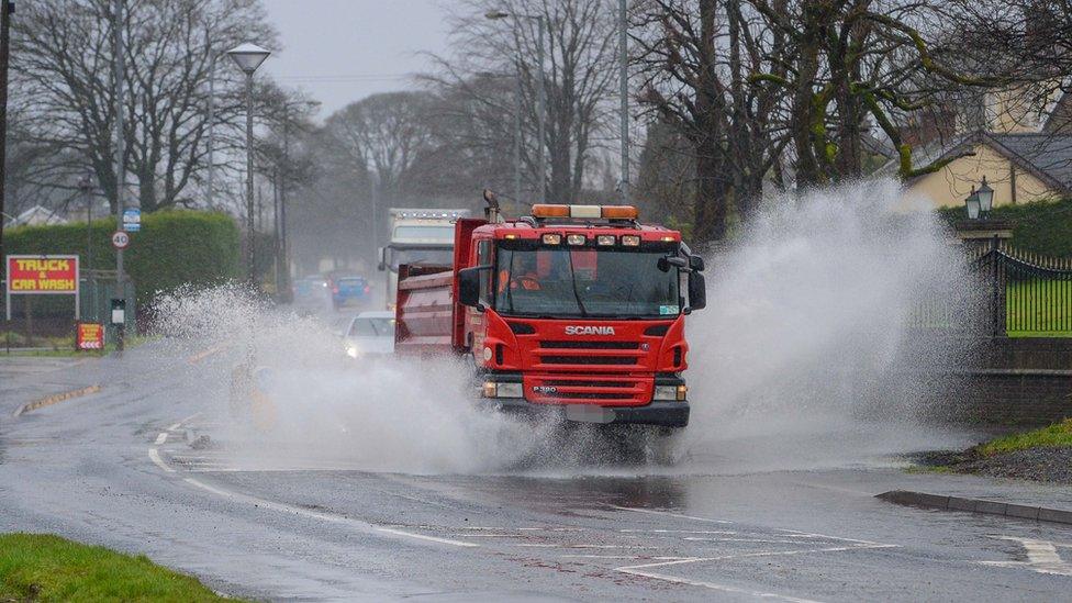 Lorry drives through flooded road