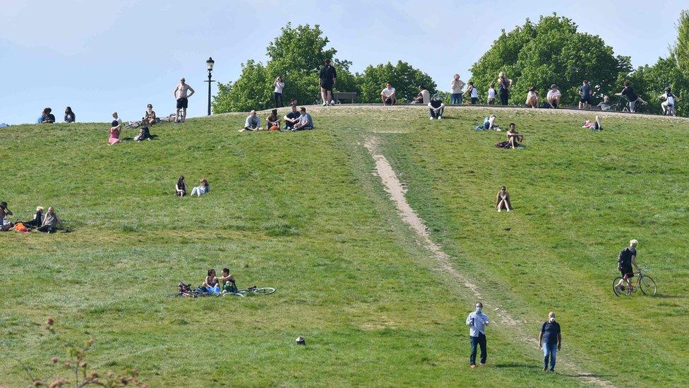 People are dotted about relaxing in the sunshine on Primrose Hill in London on May 7, 2020 as life continues in Britain under a nationwise lockdown to slow the spread of the novel coronavirus.