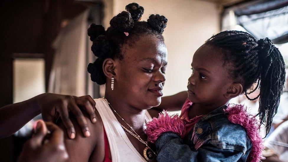 Mother holds daughter in vaccination room