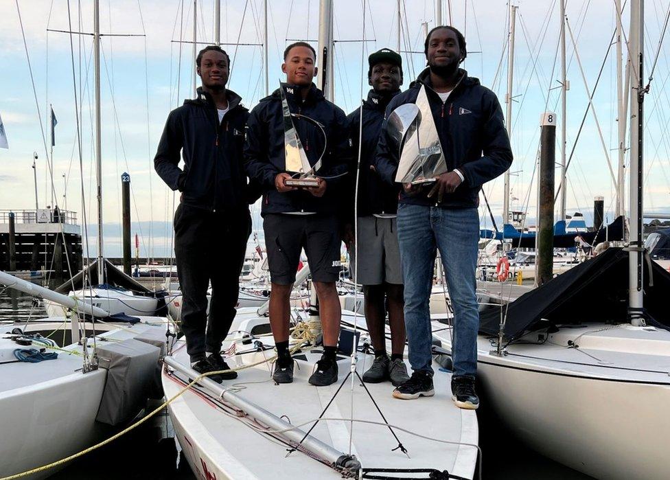 4 men on top of a sailing boat.