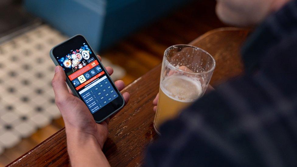 Man gambling on smartphone in pub (stock image)