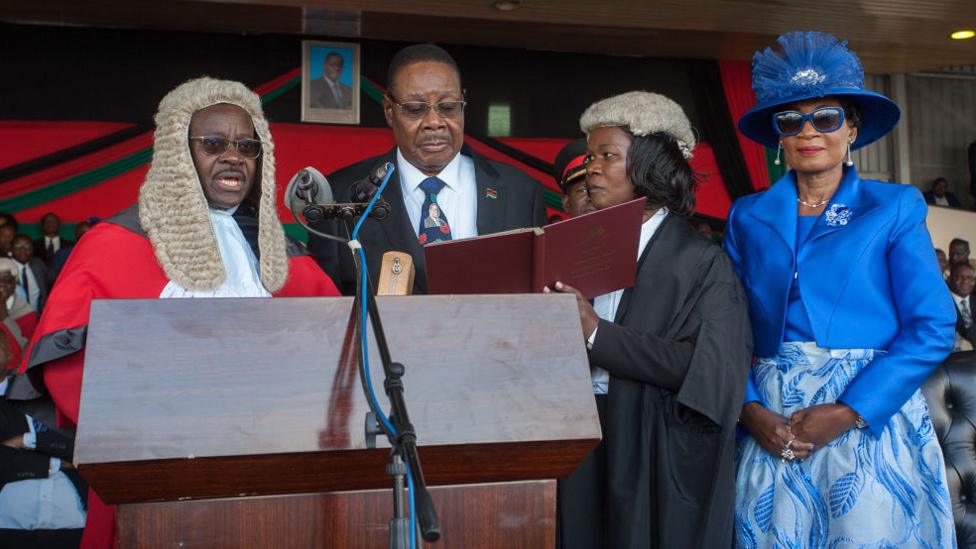 Malawi's President elect Arthur Peter Mutharika is sworn in for his second term by Chief Justice Andrew Nyirenda (L) and Registrar of the high Court and Supreme Court Of appeal (2R) as First Lady Gertrude Mutharika looks on