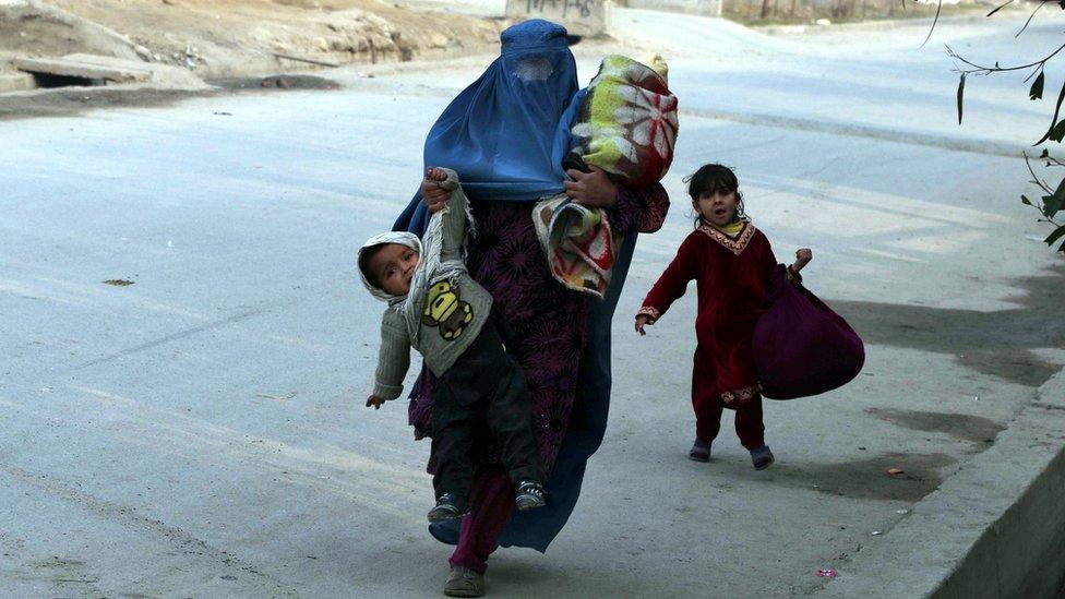 Afghan woman and her children run for cover in Jalalabad on 24 January 2018