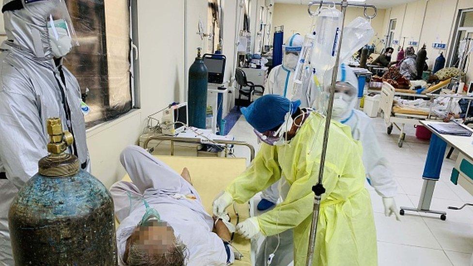 Afghan doctors help patients to breath through oxygen mask in Afghan-Japan special hospital for Covid-19 patients in Kabul, Afghanistan