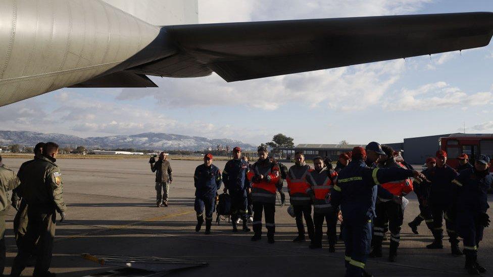 A group of rescuers stand near the entrance to a plane