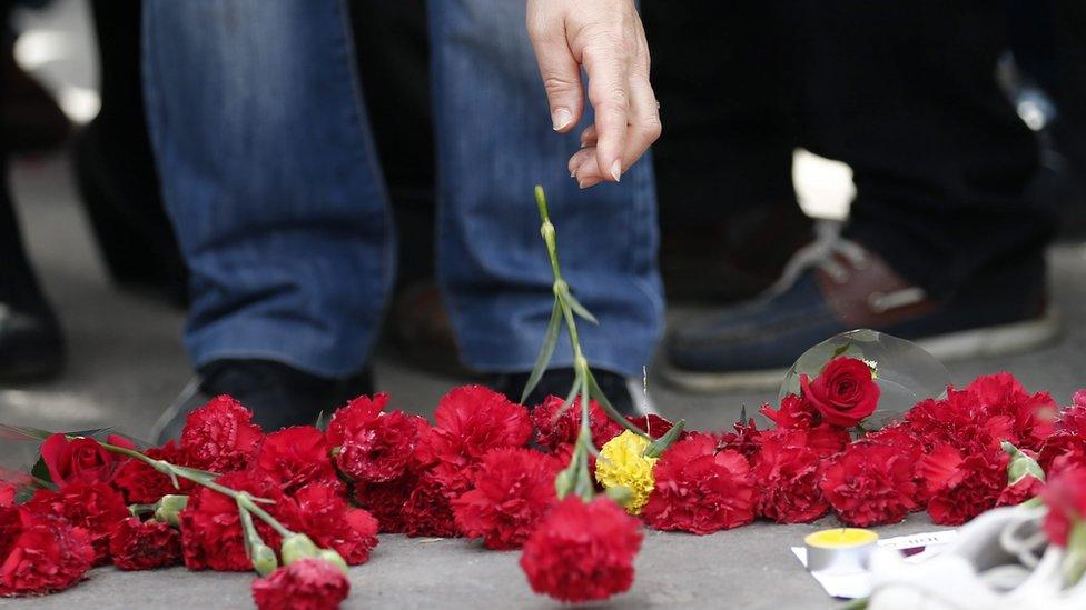 People place flowers on the ground second day after the explosions after the anti-government protest in Ankara Turkey