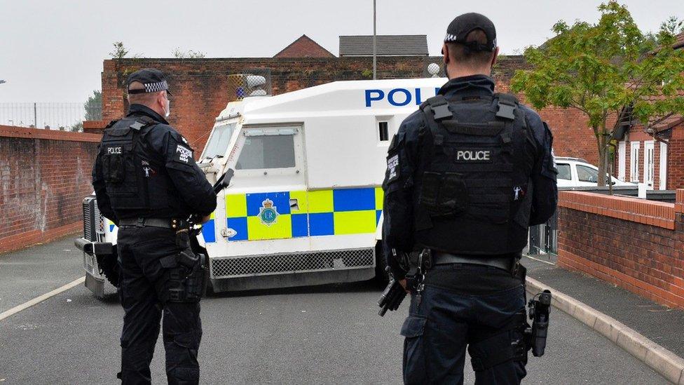 Police vehicle and armed officers in street