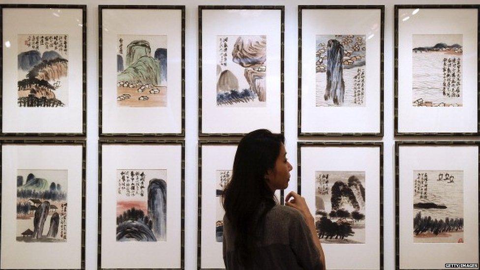 A woman inspects artwork by Chinese artist Qi Baishi entitled 'Landscapes' during a China Guardian auction preview in Hong Kong.