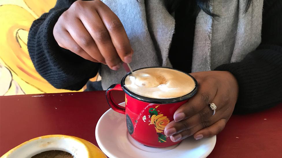 Muna Ahmed stirring a cup of coffee