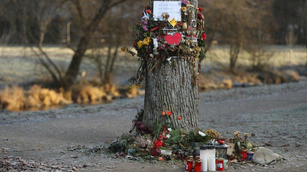 Flowers, candles and messages left by mourners adorn a tree near the spot where the medical student was raped and murdered