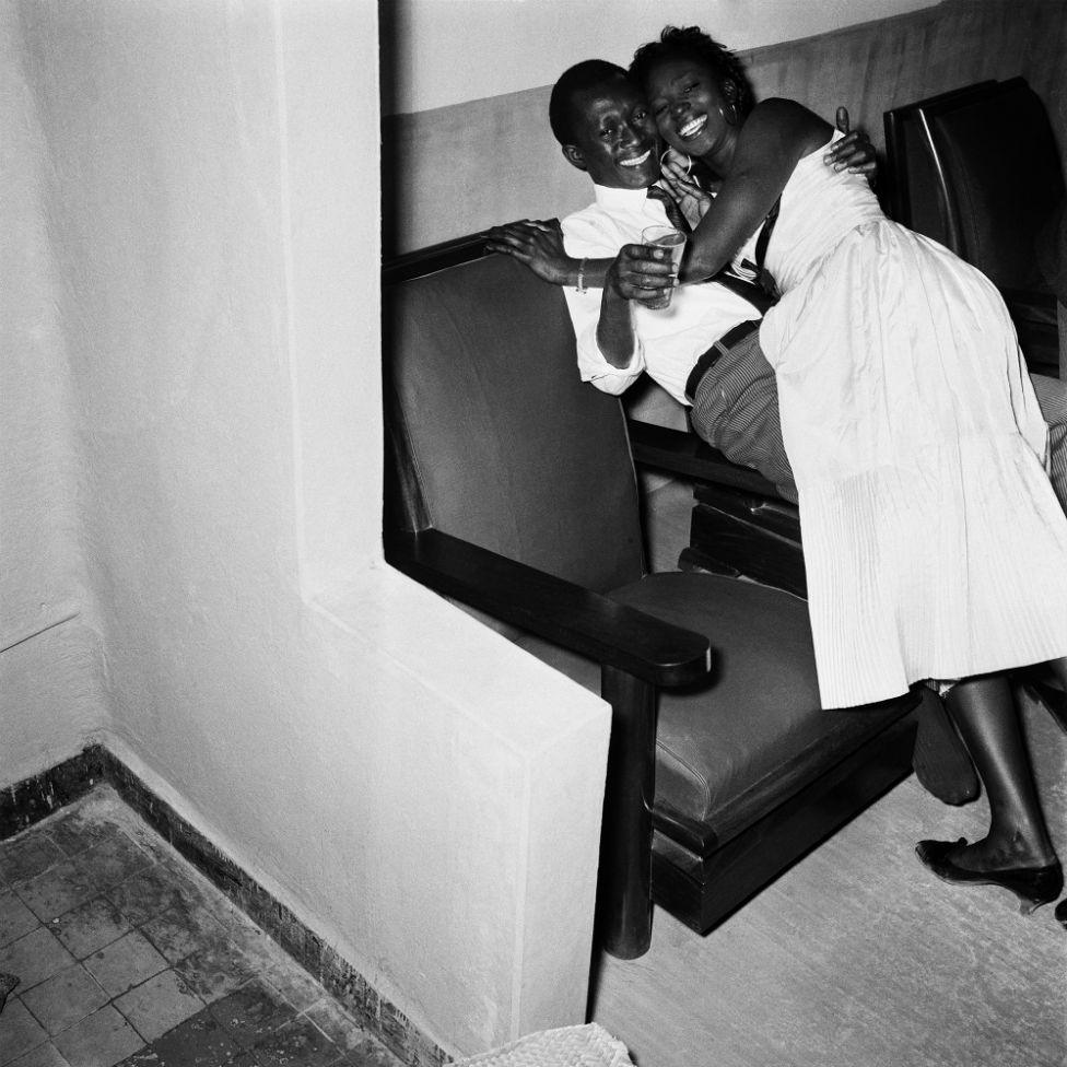 A young man and woman smile for the camera as they embrace.