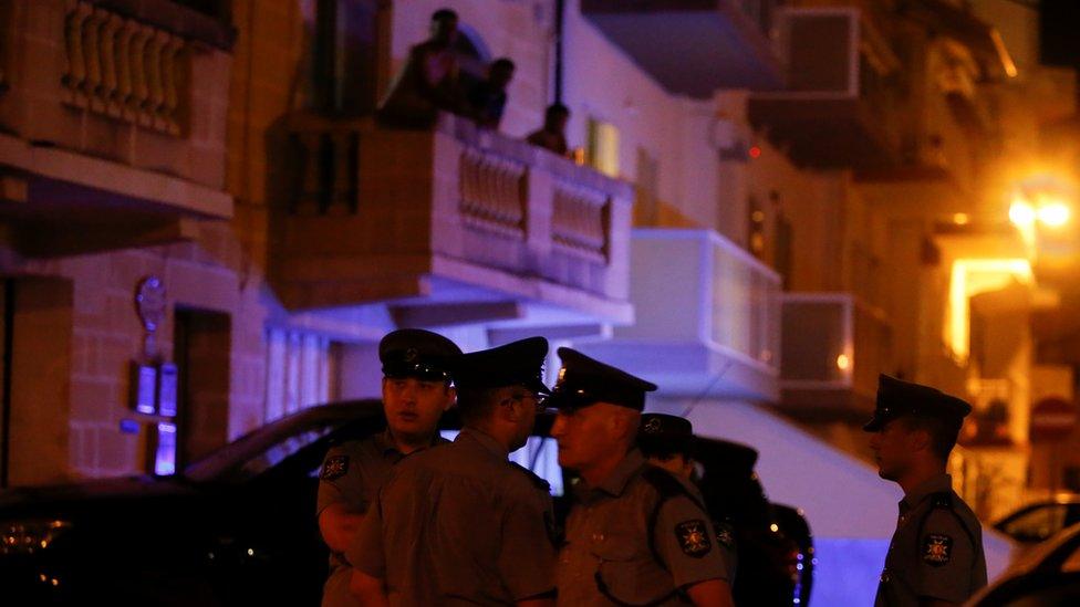 Police officers stand near the home of Melvyn Theuma on 22 July