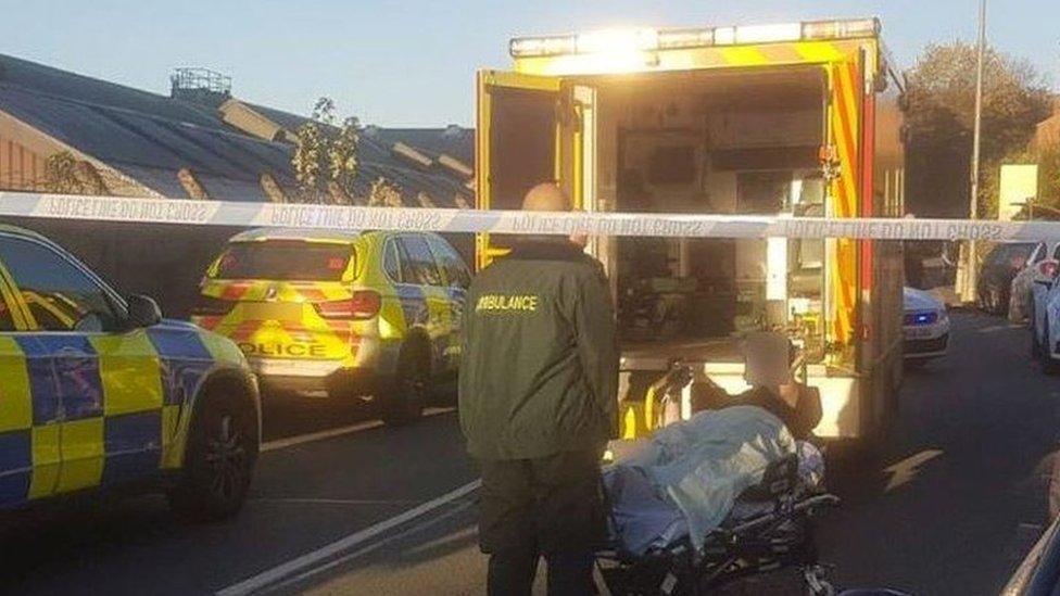 The injured policeman lies on a stretcher next to an open ambulance