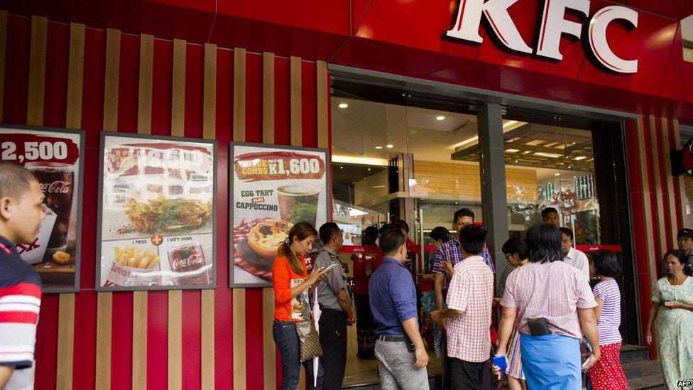 People wait outside of KFC's first branch restaurant in the commercial capital of Yangon