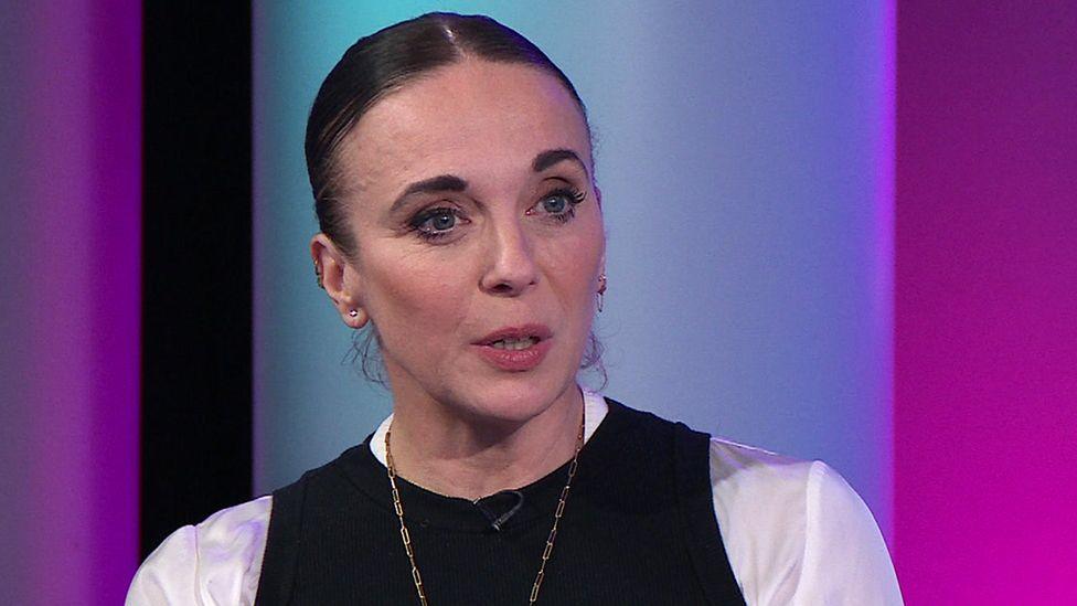 Amanda Abbington looks towards the camera against a purple and blue background as she appears on while speaking on Newsnight, 2 October 