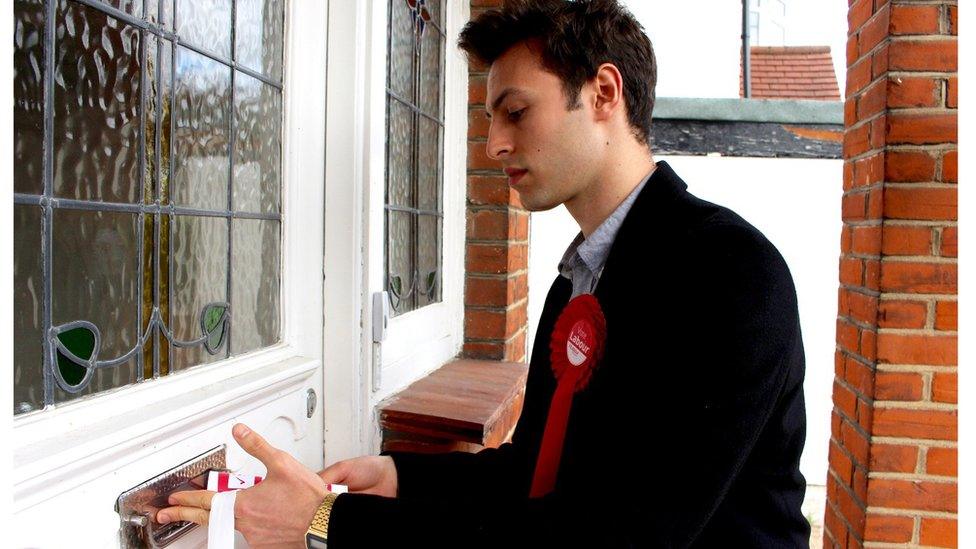 Josh Abey posting campaign leaflets through a door