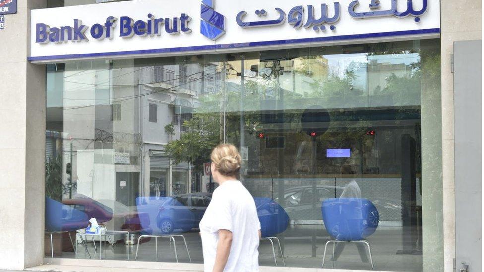 Man walks in front of branch of Bank of Beirut