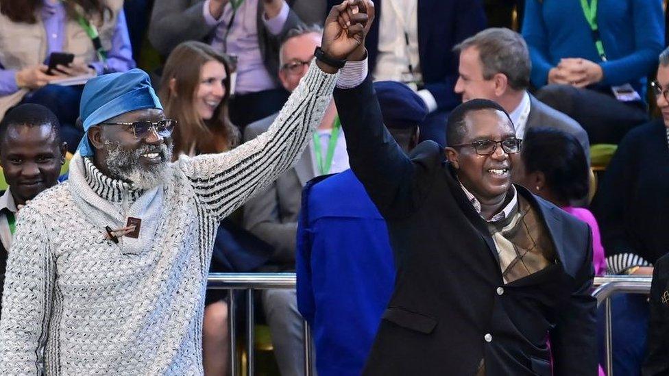 Presidential contenders in the recent Kenya general elections, George Wajackoya (L) of Roots Party and David Mwaure (R) of Agano Party raise their clasped hands after they arrived at the National Tallying Centre in the Bomas of Kenya concurrently in Nairobi on August 15, 2022