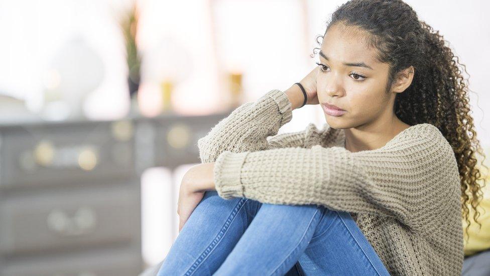 girl-sat-alone-in-room-looking-upset