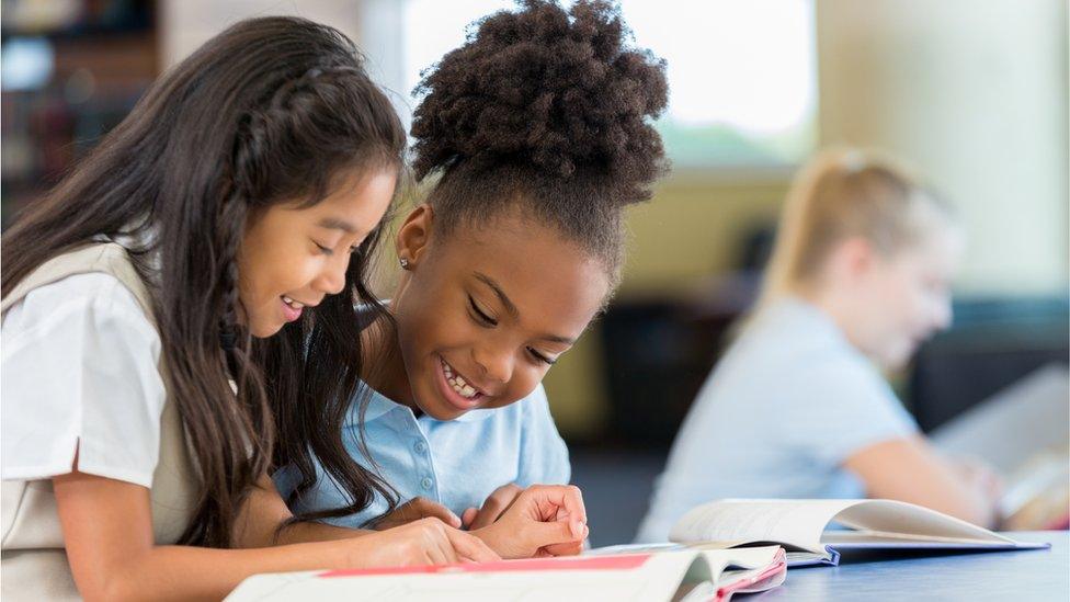 Schoolgirls reading a book together at school