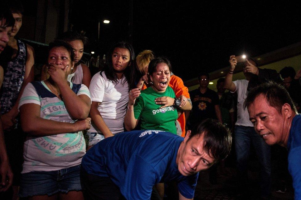 This picture taken on 5 January 2017, shows relatives crying as coroners carry away the body of an alleged drug dealer killed during a drug buy bust operation in Manila.