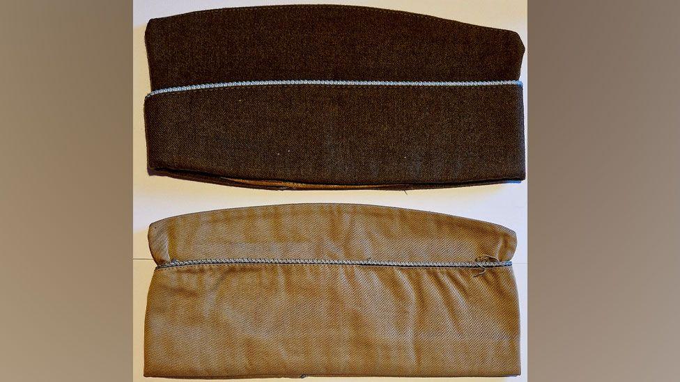 Earl Thurman's garrison caps. One is dark brown with blue piping across the middle. The other is light brown with blue piping across the middle. They are both folded flat and lengthways