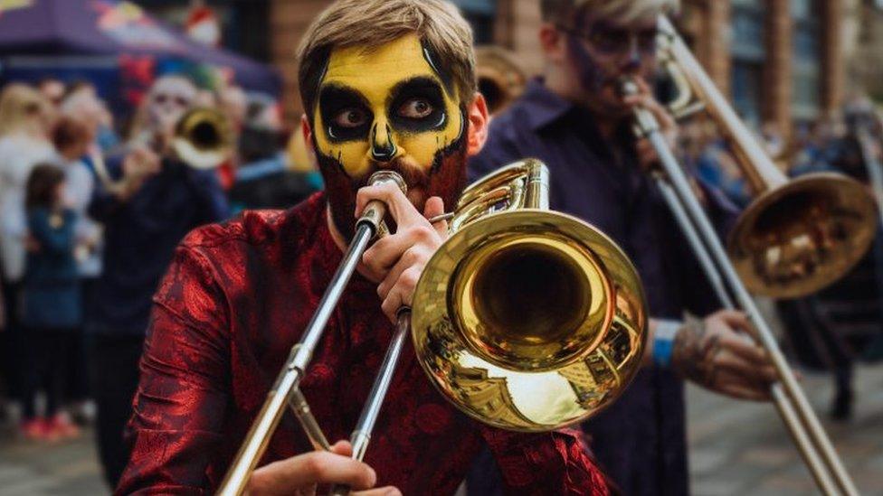 Two men with painted faces playing trumpets