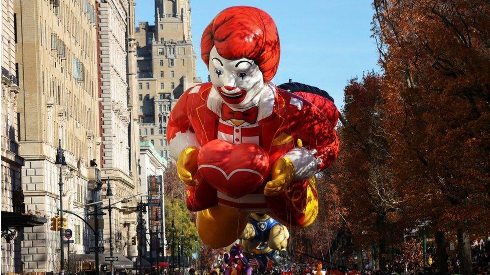 A balloon depicting Ronald McDonald floats through the street during Macy's Thanksgiving Day Parade