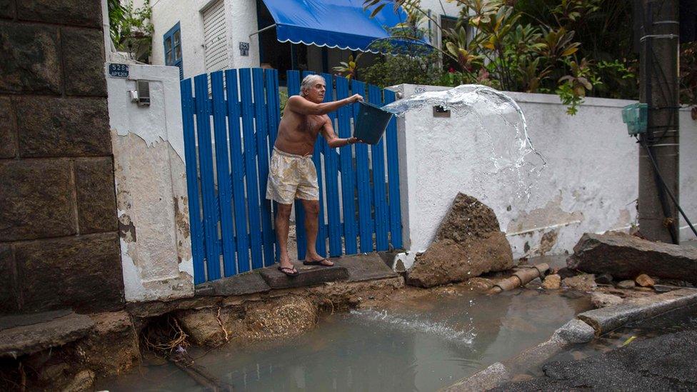 A man takes water out of the driveway of his home