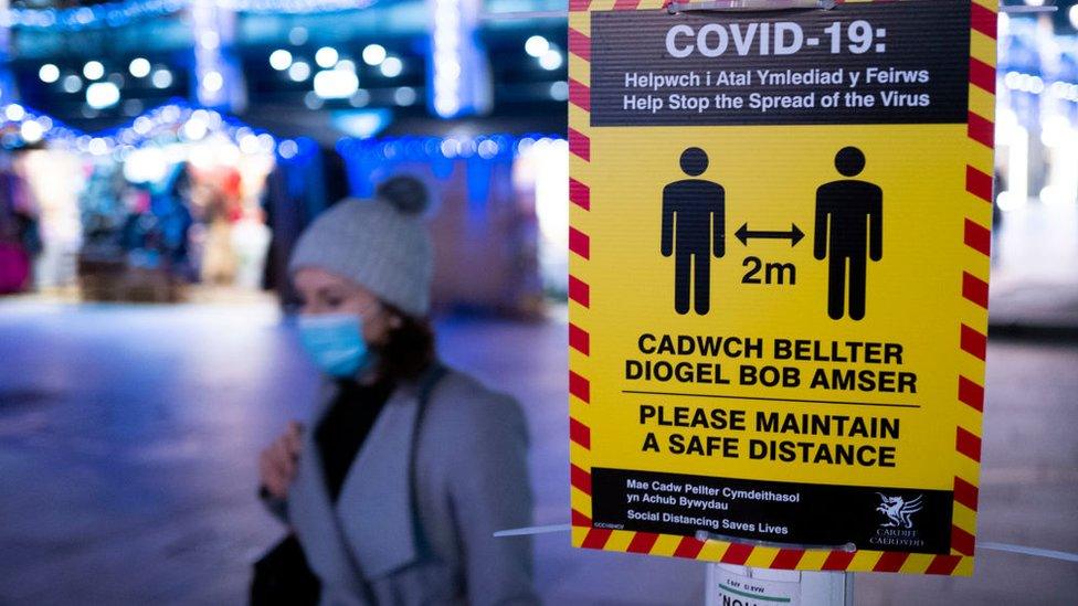 woman walking past social distancing sign