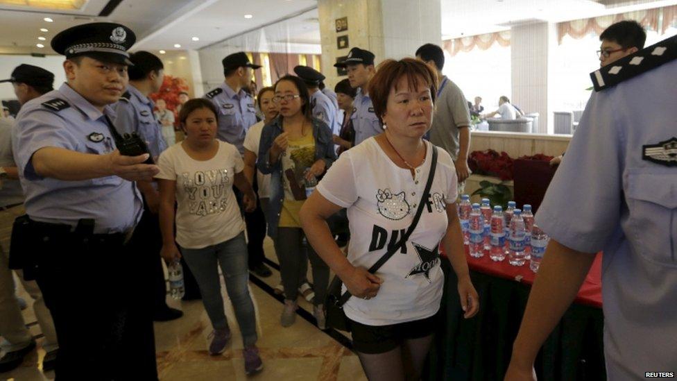 Relatives are guided by police outside a news conference - 15 August