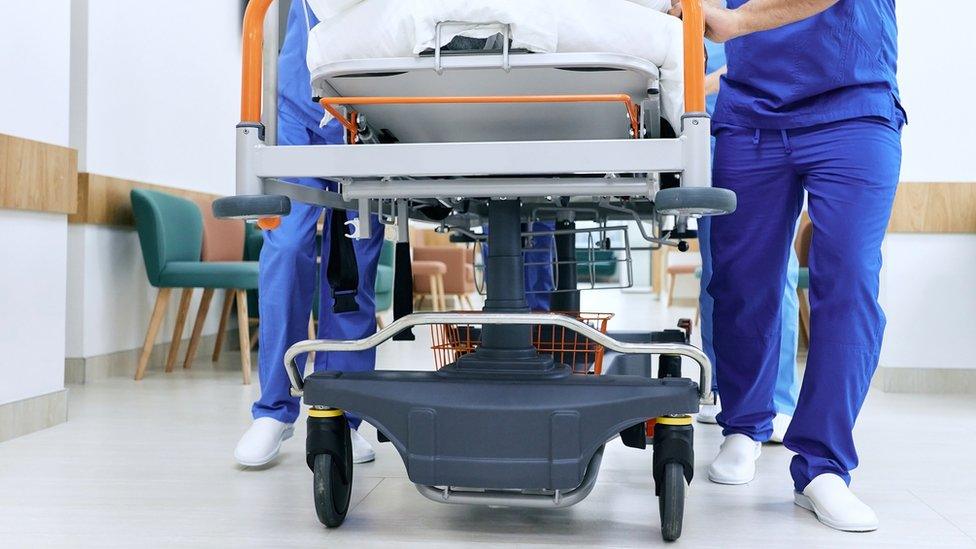 Medical staff pushing patient on medical gurney at emergency department, bottom view