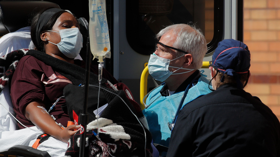 Medics tend to a woman being admitted to hospital on a trolley in New York