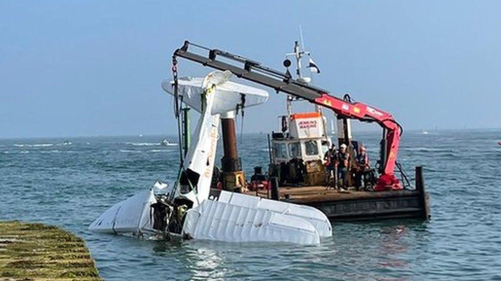 Crane lifting plane out of water