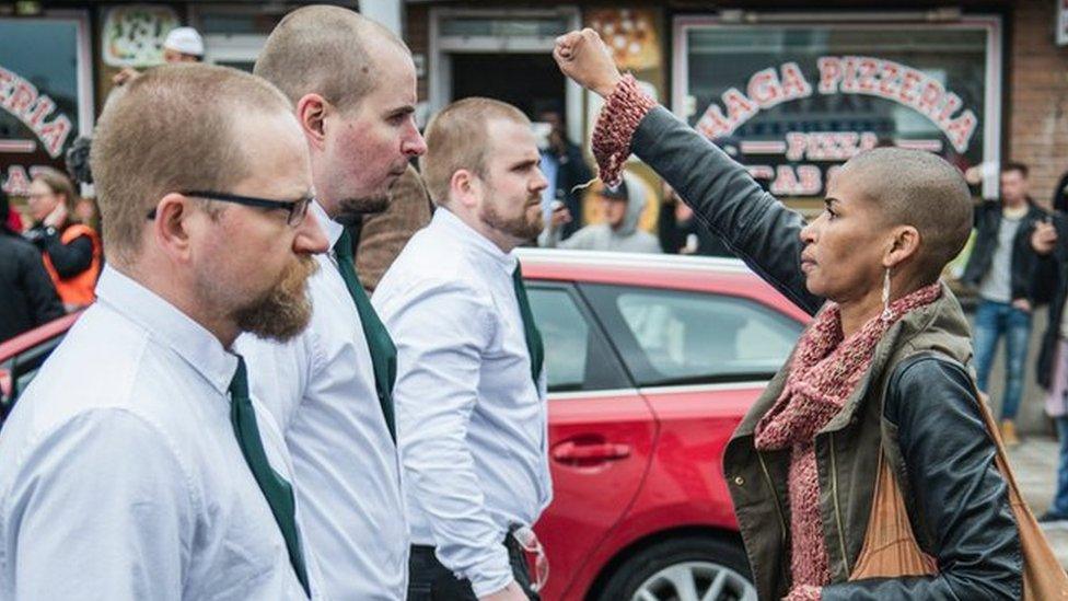 A lone woman stands with raised fist opposite the uniformed demonstrators in Sunday's Nazi demonstration in Borlange, Sweden