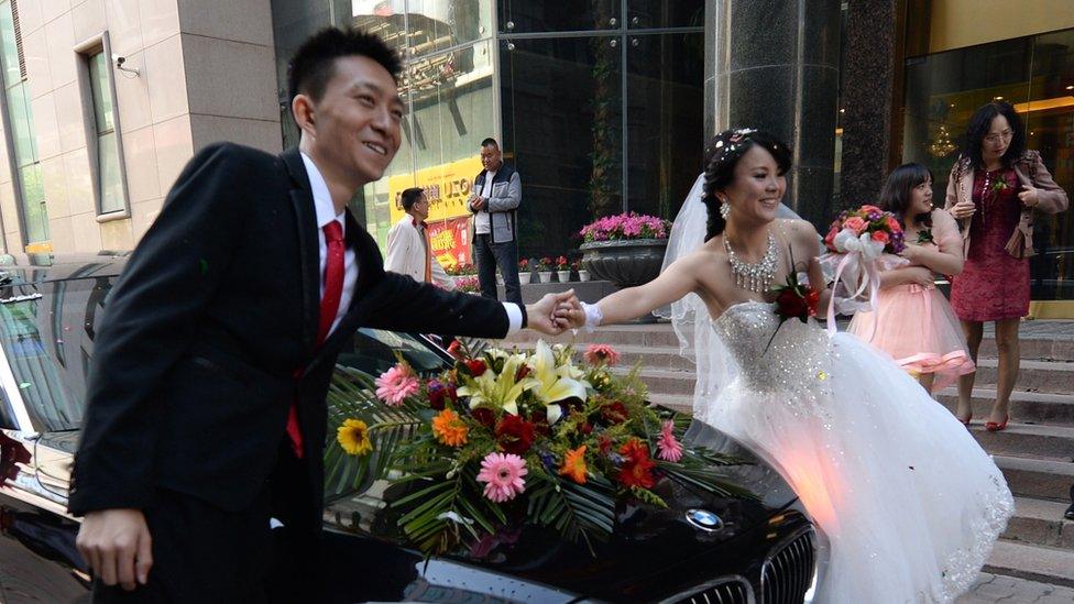 A Chinese couple pose with their bridal car