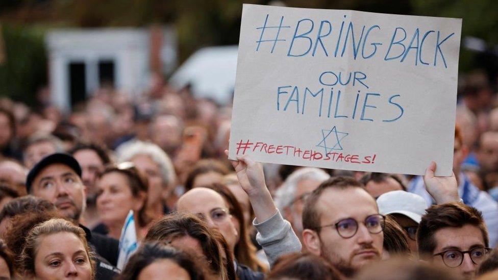 Crowd of people with sign saying "bring back our families"