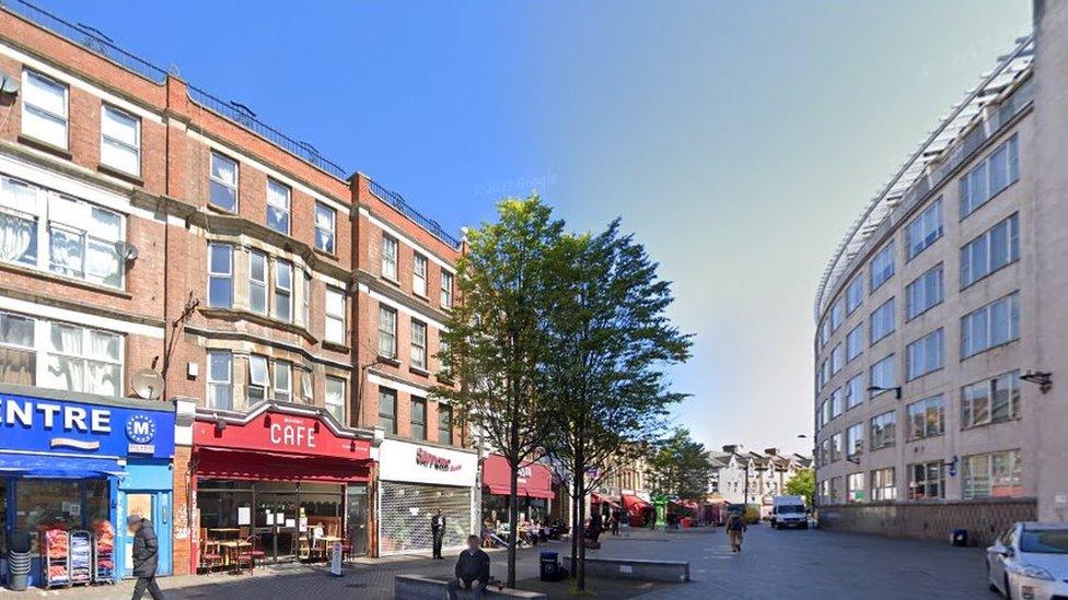 StreetView image of Catford Broadway with shops, a tree and seating