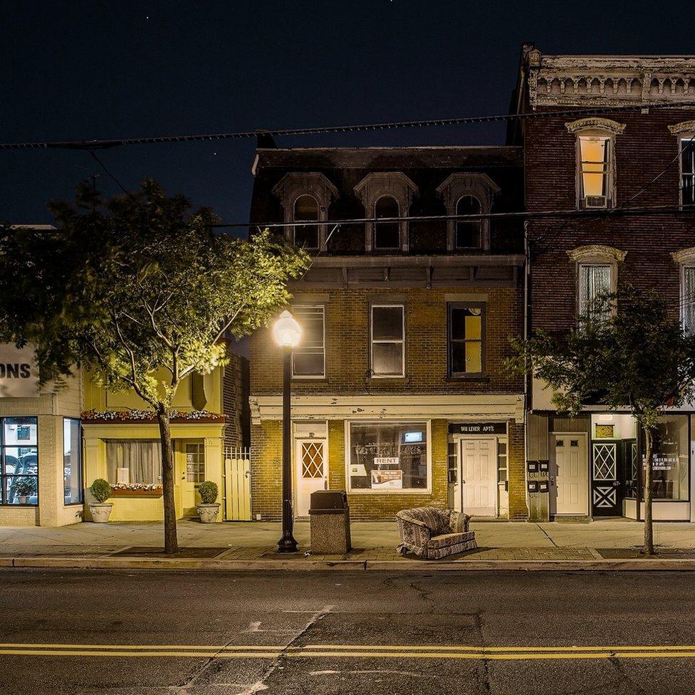 A night view of an empty street with an abandoned armchair in the middle of the pavement