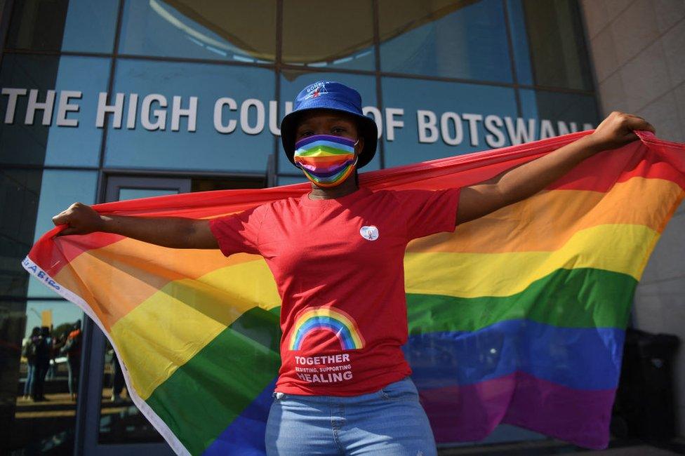 An activist waves the LGBTQ flag outside the court.