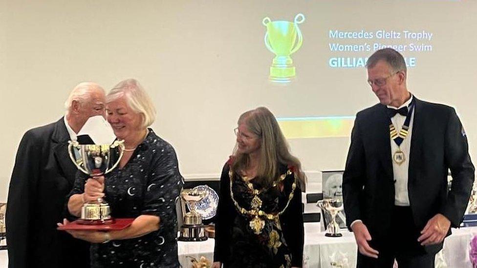 Deborah Vine collecting one of the trophies with three people from the Channel Swimming Association looking on