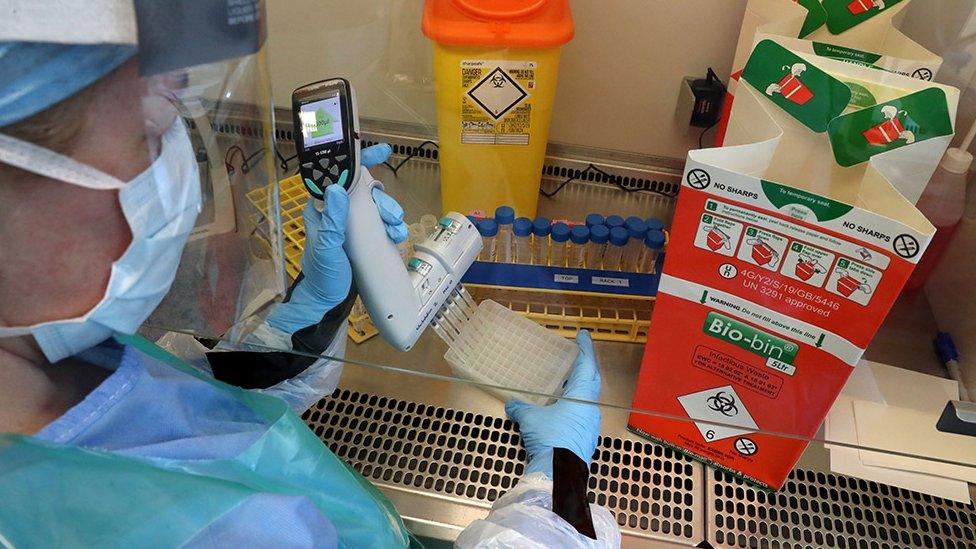 A technician carries out a sample transfer during the opening of the new COVID-19 testing lab at Queen Elizabeth University Hospital