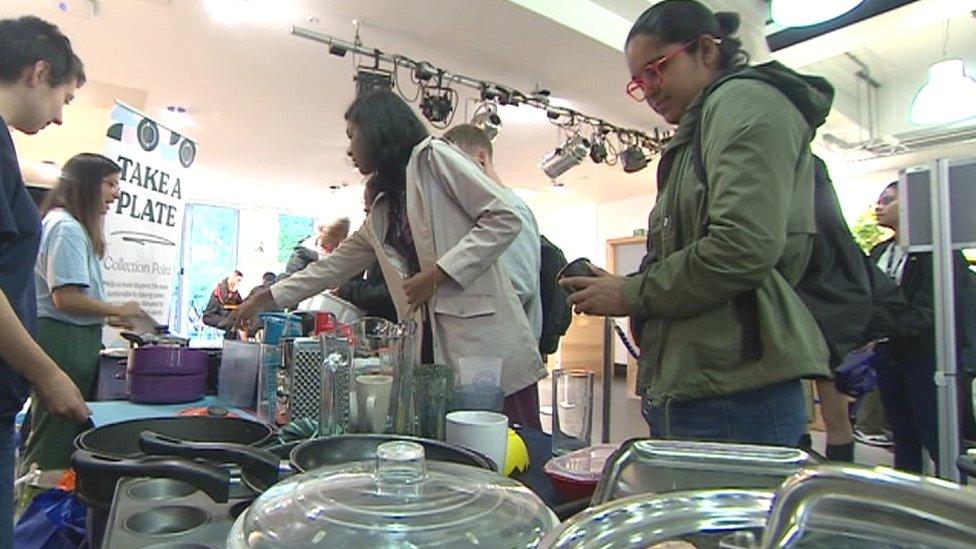 A group of people looking at kitchen items at take a plate event