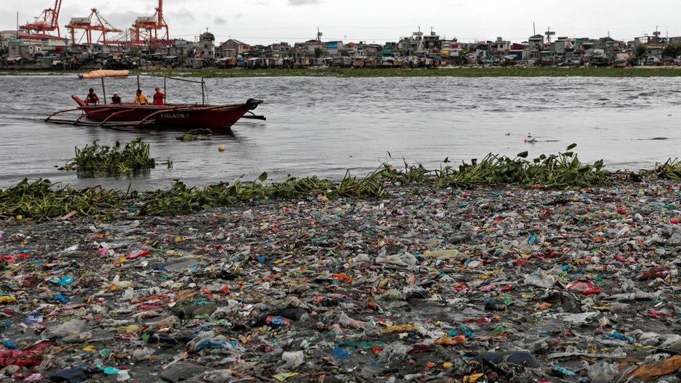 Boat prepares to dock on the rubbish filled shore of Baseco Beach