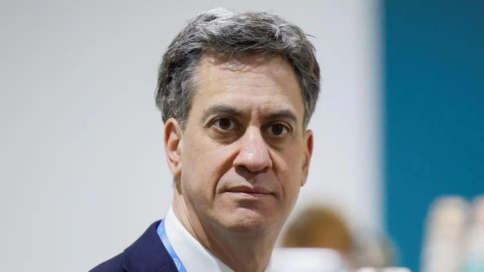 Labour politician Ed Miliband is pictured looking just beyond the camera. He is wearing a blue suit jacket with a white shirt